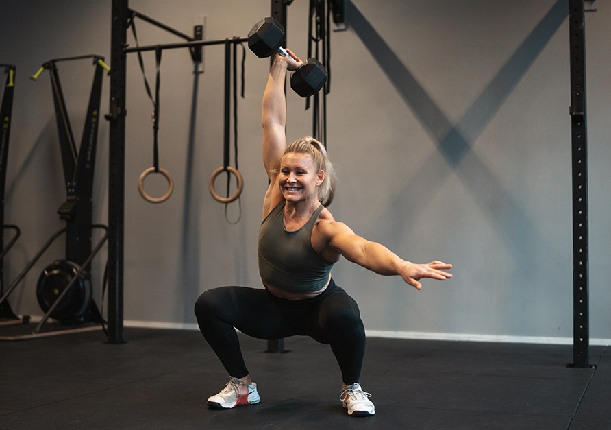 En kvinde tr�ner med h�ndv�gte i et fitnessmilj�.